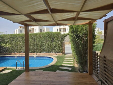 Kleiner privater Pool mit Terrasse und Sonnenliegen in einem Garten